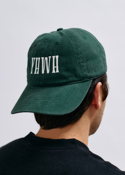 Green cap with 'YHWH' text worn by a person on a light gray background